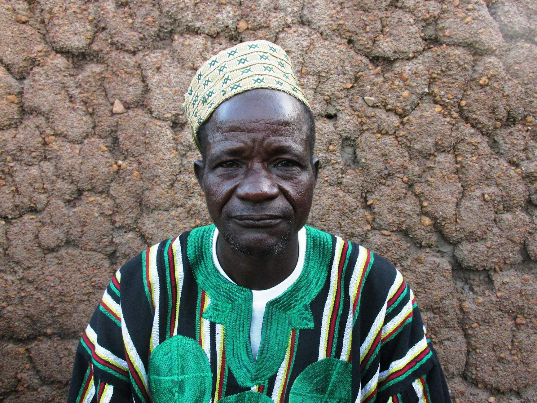 Elderly man in traditional clothing sitting in Togo village.