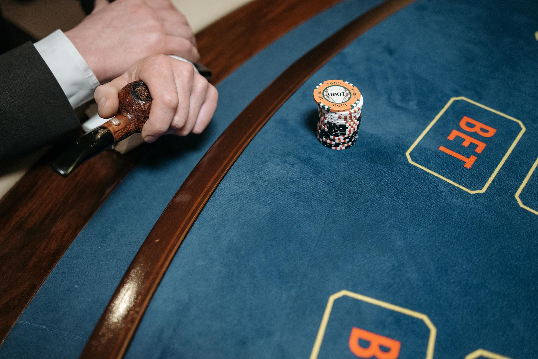 Detailed view of a casino gaming table with poker chips and a wooden pipe on the side.